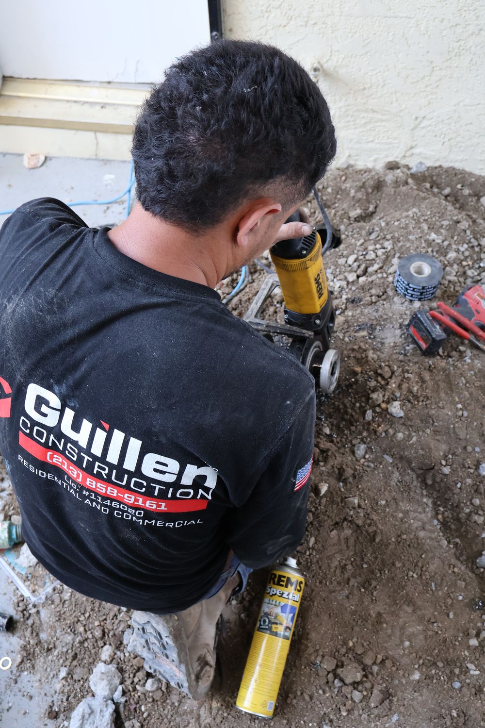 Guillen Construction crew member in uniform threading pipe on a repipe job